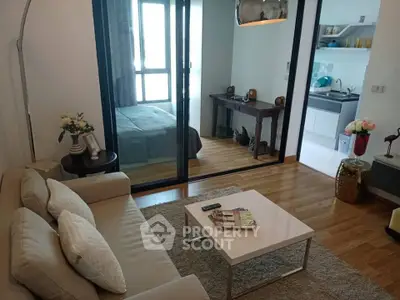 Modern living room with cozy sofa, glass partition, and view into stylish bedroom and kitchen.