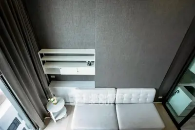 Modern living room with sleek gray walls and stylish white furniture, featuring a cozy sofa and elegant shelving.