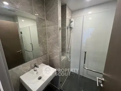Modern bathroom with sleek design featuring glass shower and stylish sink.