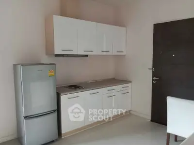 Modern kitchen with sleek cabinets and stainless steel fridge in minimalist apartment.