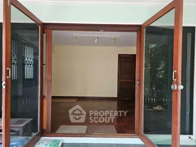 Spacious room with wooden flooring and large glass doors opening to a garden view.