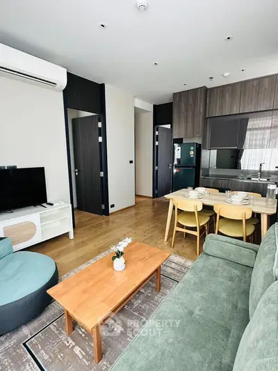 Modern living room with open kitchen, featuring stylish furniture and wooden flooring.