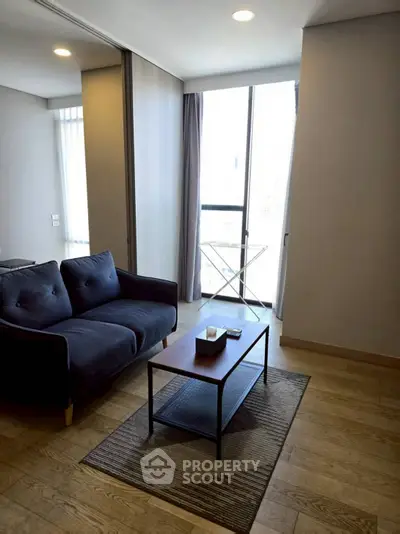 Modern living room with cozy sofa and natural light from large window.