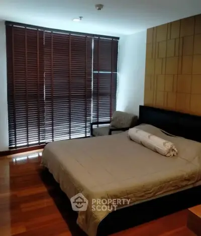 Cozy bedroom with wooden flooring and modern blinds, perfect for relaxation.