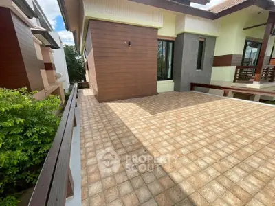 Spacious tiled balcony with modern exterior design and lush greenery view.