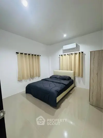 Modern bedroom with sleek design, featuring a comfortable bed, air conditioning, and minimalist decor.