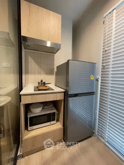 Modern compact kitchen with fridge, microwave, and stove in stylish apartment.