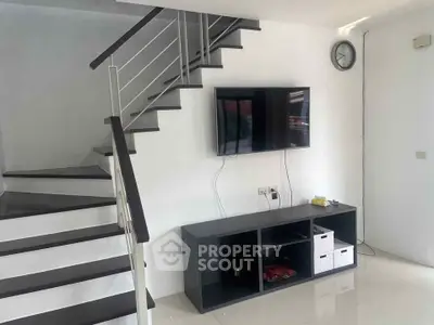 Modern living room with sleek staircase and wall-mounted TV