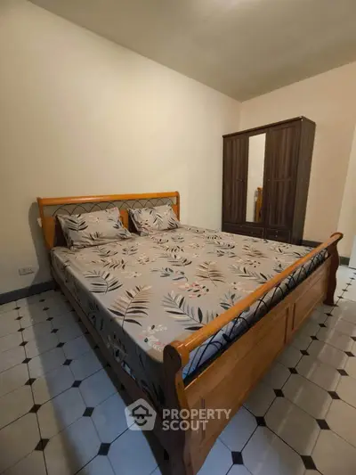 Cozy bedroom with wooden bed and wardrobe, featuring stylish tiled flooring.