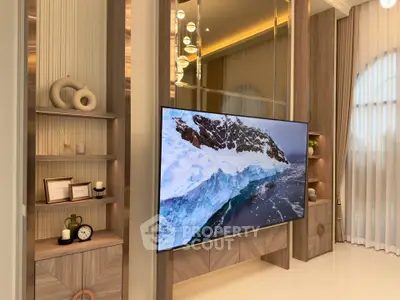 Luxurious living room with modern decor and large flat-screen TV, featuring elegant shelving and ambient lighting.