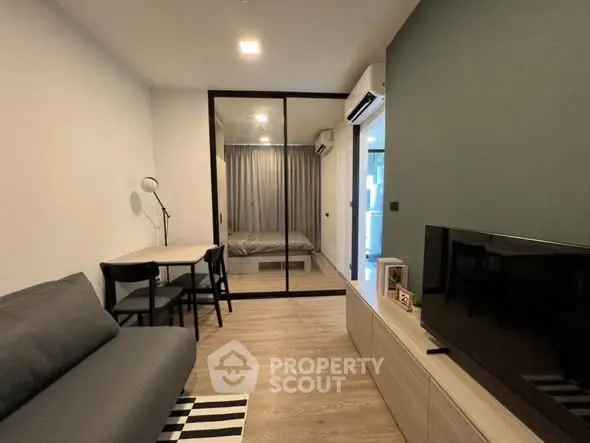 Modern living room with sleek furniture and glass partition leading to bedroom, perfect for urban living.