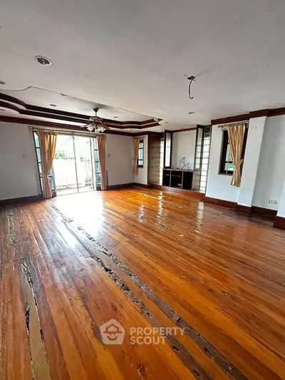Spacious living room with wooden flooring and large windows for natural light.