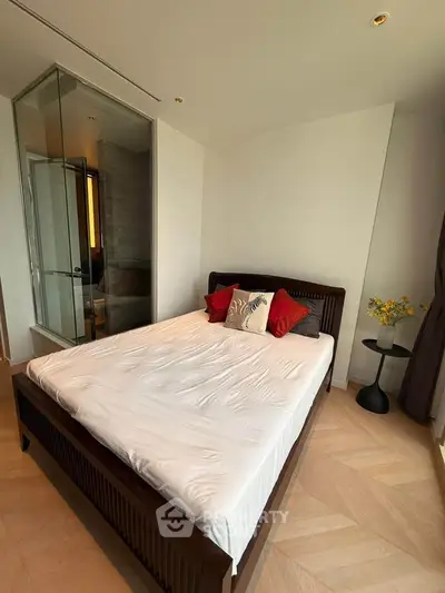 Modern bedroom with stylish decor and glass-enclosed ensuite bathroom