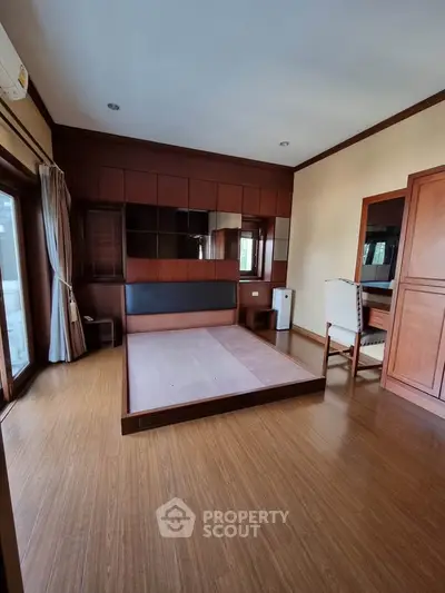 Spacious bedroom with wooden flooring and built-in wardrobe, perfect for modern living.