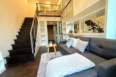 Modern loft-style living room with mezzanine, sleek staircase, and cozy seating area.