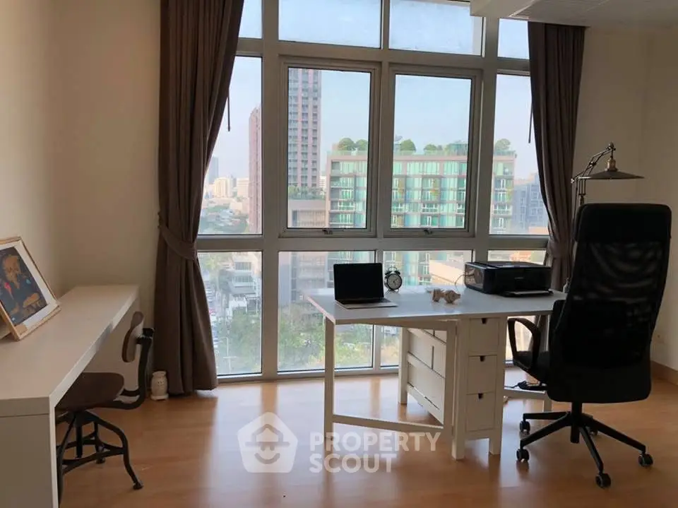 Bright study room with large windows and city view, featuring modern desk and chair.