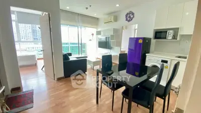 Modern open-plan living room with kitchen, featuring sleek furniture and city view.