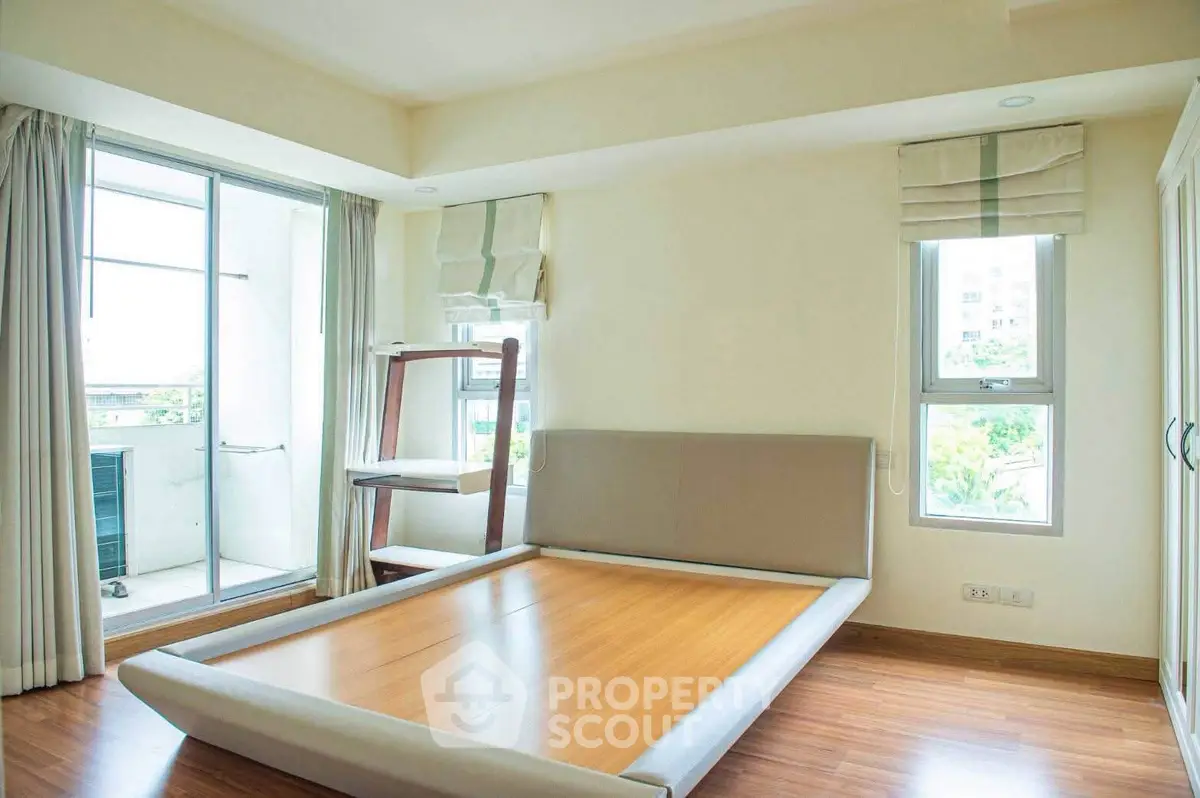 Spacious bedroom with large windows and balcony access in modern apartment