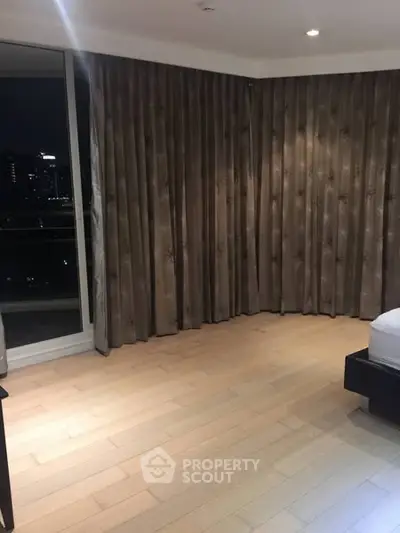 Spacious bedroom with city view and elegant curtains