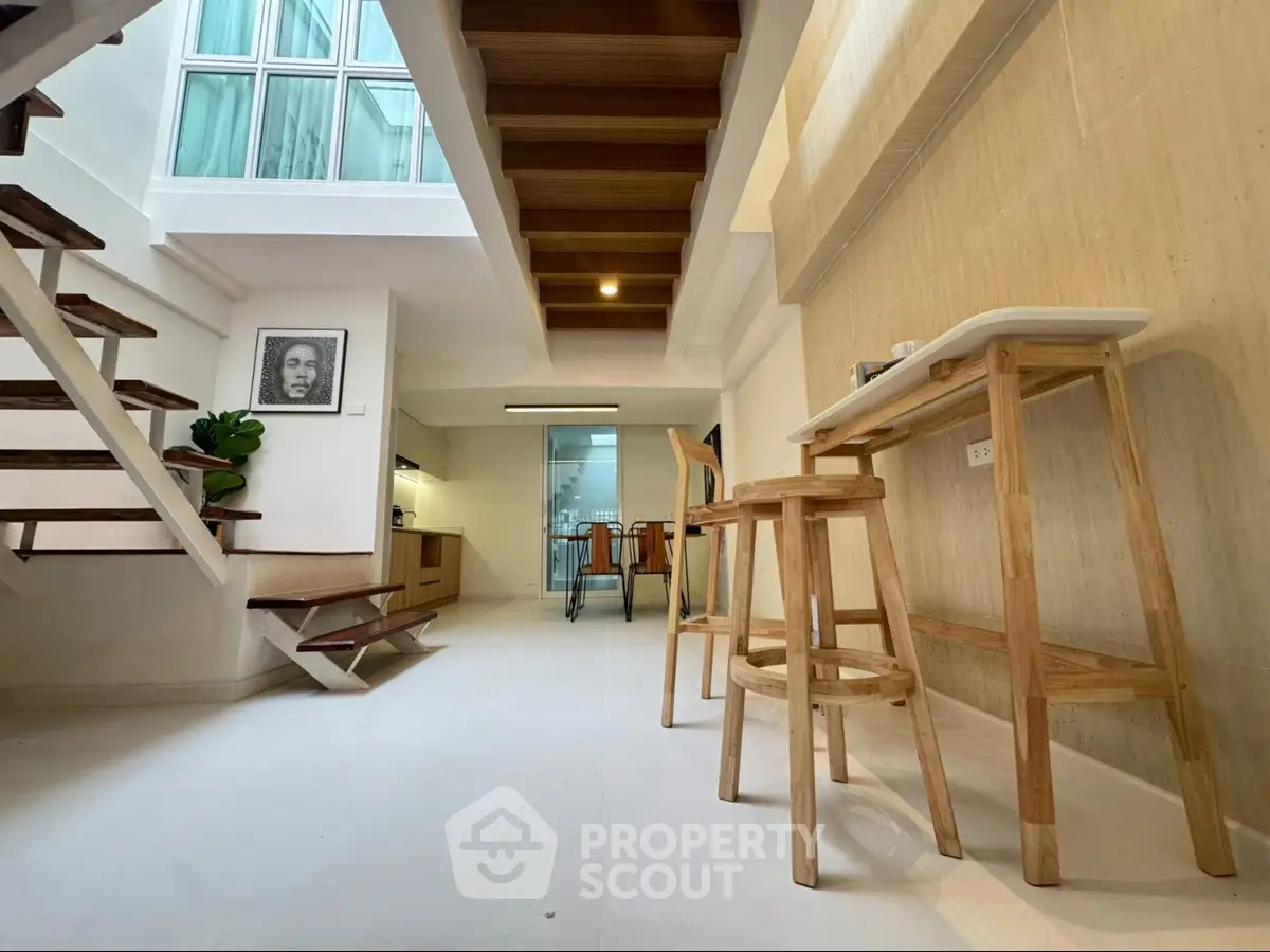 Modern open-plan interior with stylish wooden staircase and minimalist kitchen design.