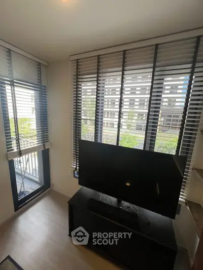 Modern living room with large windows and a sleek TV setup, offering a bright and airy ambiance.