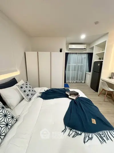 Modern bedroom with stylish decor, featuring a cozy bed, air conditioning, and a compact workspace.