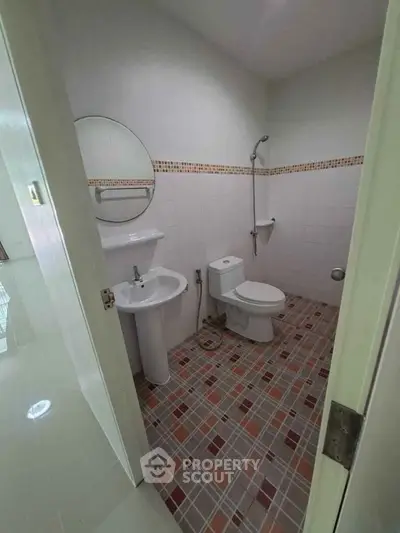Compact bathroom with tiled floor and modern fixtures in a cozy apartment.