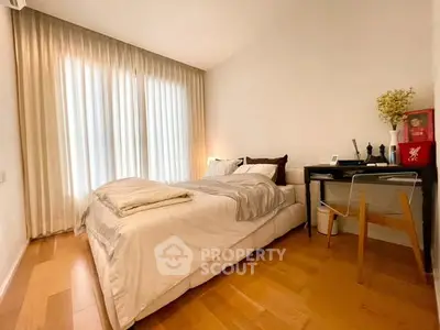 Cozy bedroom with elegant decor and natural light, featuring a comfortable bed and stylish workspace.