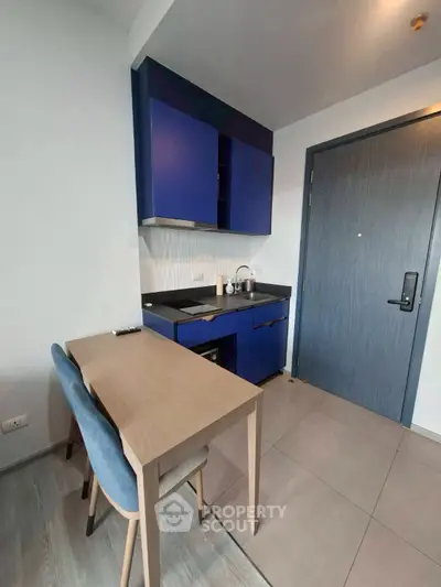 Modern compact kitchen with blue cabinets and dining area in stylish apartment