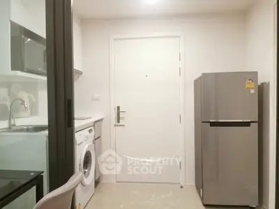 Compact kitchen with washing machine and fridge in modern apartment