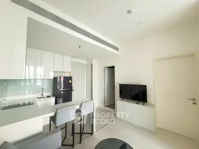 Modern open-plan living room with sleek kitchen and stylish furnishings in a contemporary apartment.