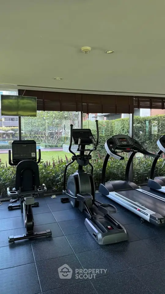 Modern gym with cardio equipment and garden view in luxury residential building.