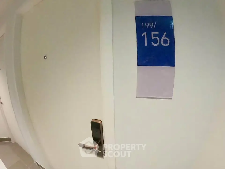 Modern apartment entrance with digital lock and room number signage.