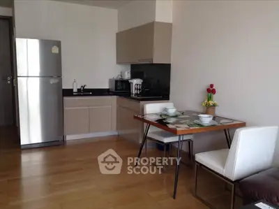 Modern kitchen with dining area featuring sleek cabinets and wooden flooring.