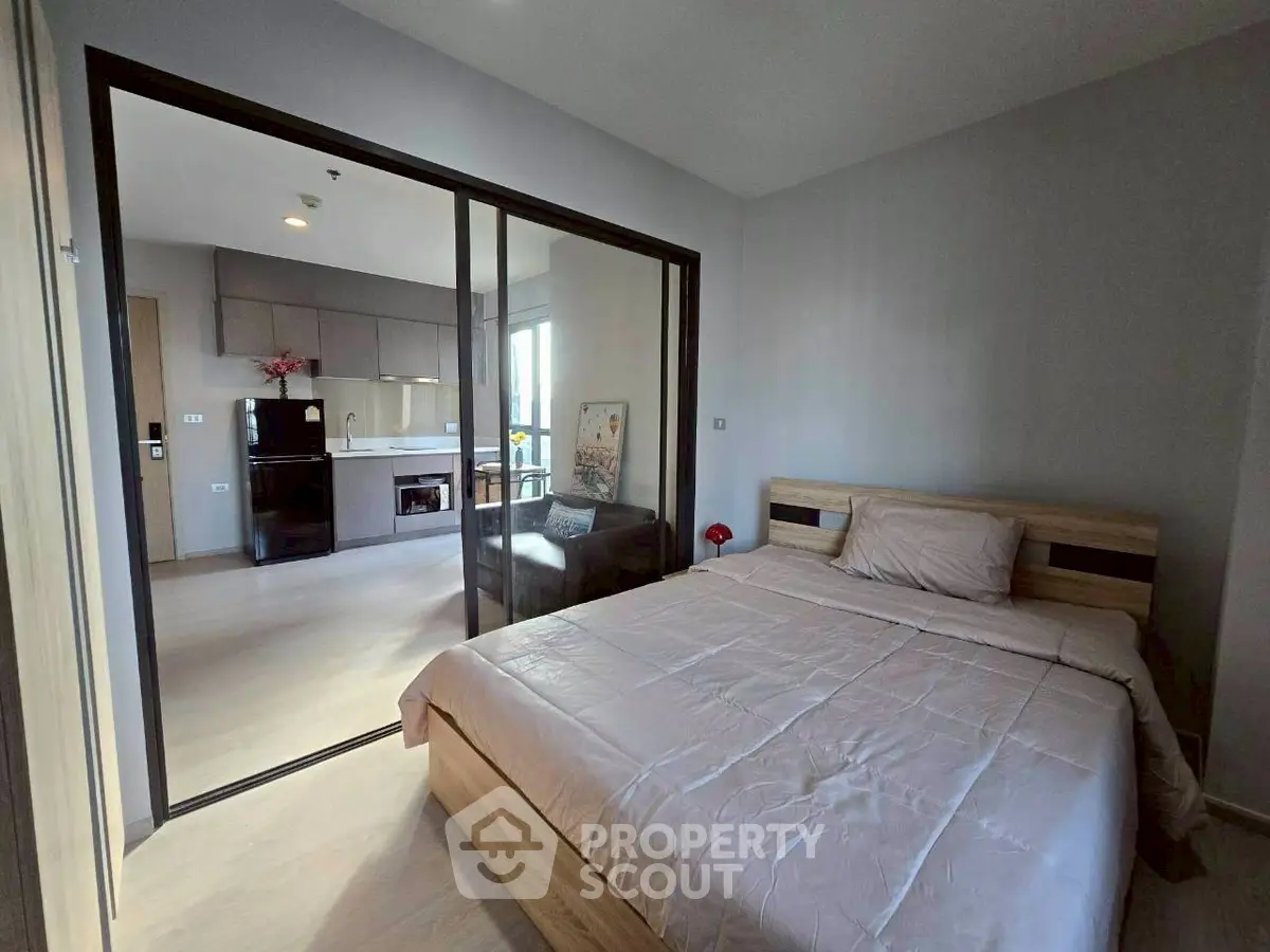 Modern bedroom with glass partition leading to a stylish kitchen area.