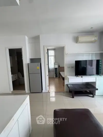 Modern apartment interior with open layout, featuring a sleek kitchen, cozy living area, and bedroom view.