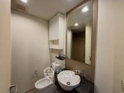 Modern bathroom with sleek fixtures and large mirror in a contemporary apartment.