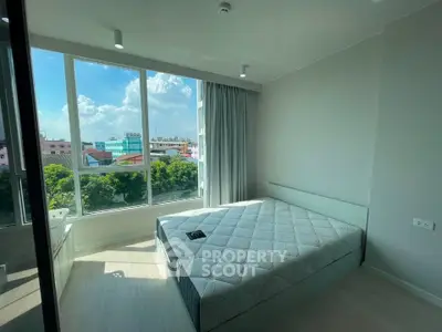 Bright bedroom with large windows offering a stunning city view, featuring a comfortable bed and modern decor.