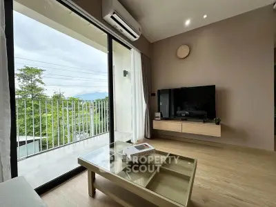 Modern living room with large glass doors opening to a balcony with scenic views.