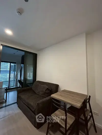 Cozy living room with dark sofa and wooden dining set in modern apartment