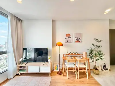 Bright modern living room with city view, stylish decor, and cozy dining area.