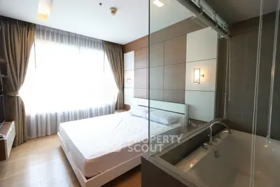 Modern bedroom with large window and bathtub, featuring elegant design and natural light.