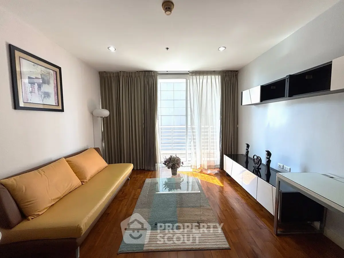 Stylish living room with modern decor, wooden flooring, and ample natural light from large windows.