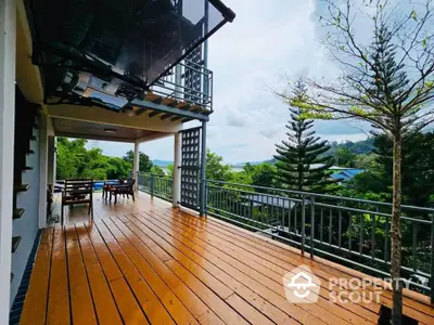 Spacious wooden balcony with scenic view of lush greenery and distant hills, perfect for relaxation.