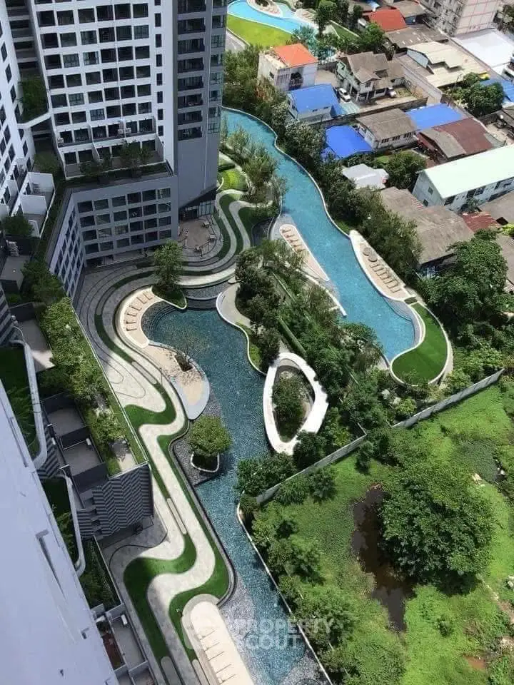 Stunning aerial view of modern residential complex with lush gardens and winding pool.