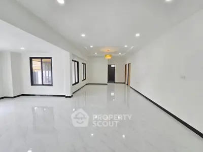 Spacious modern living room with glossy white floors and ample natural light.