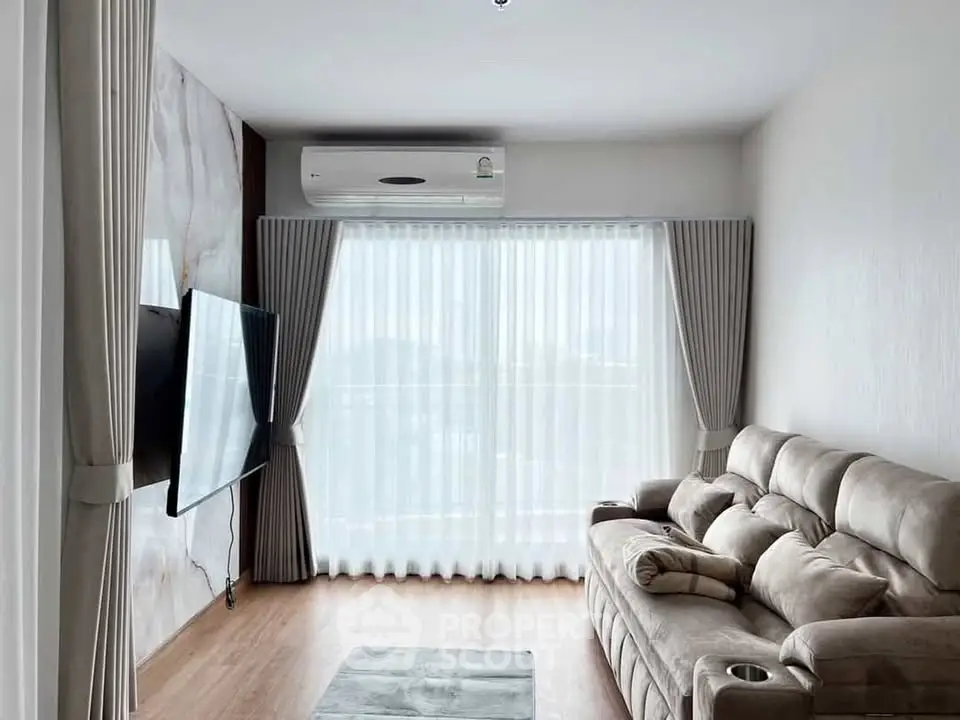 Modern living room with plush sofa, wall-mounted TV, and large window with curtains.