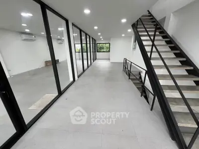 Spacious modern interior with sleek staircase and glass walls, perfect for contemporary living or office space.