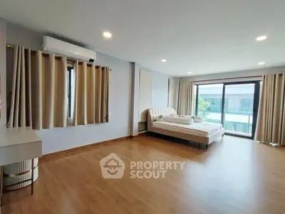 Spacious bedroom with modern decor and large windows offering natural light.