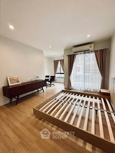 Spacious bedroom with wooden flooring and large windows for natural light